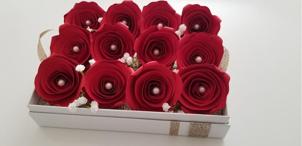 A full view of the one dozen red, paper roses sitting atop the removable tray inside the box.