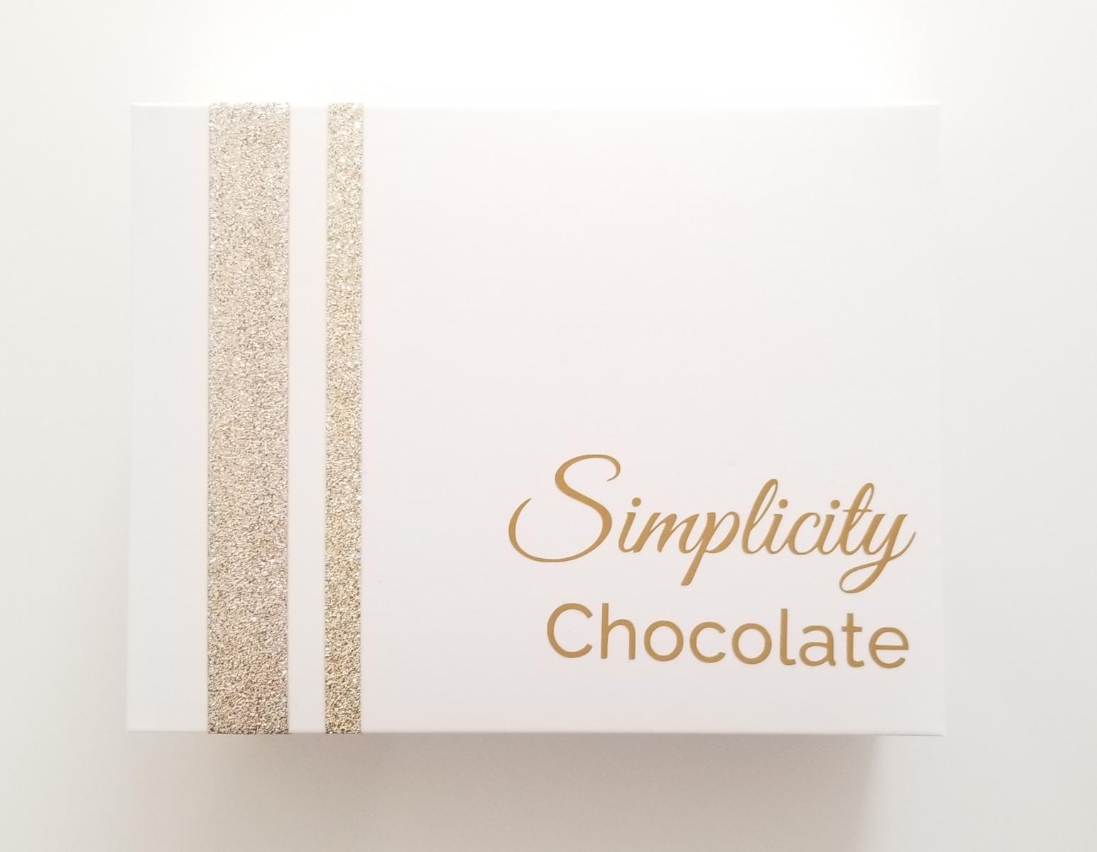 The lid of The Simplicity Chocolate Nostalgia Box with gold accents and the signature logo in gold writing.