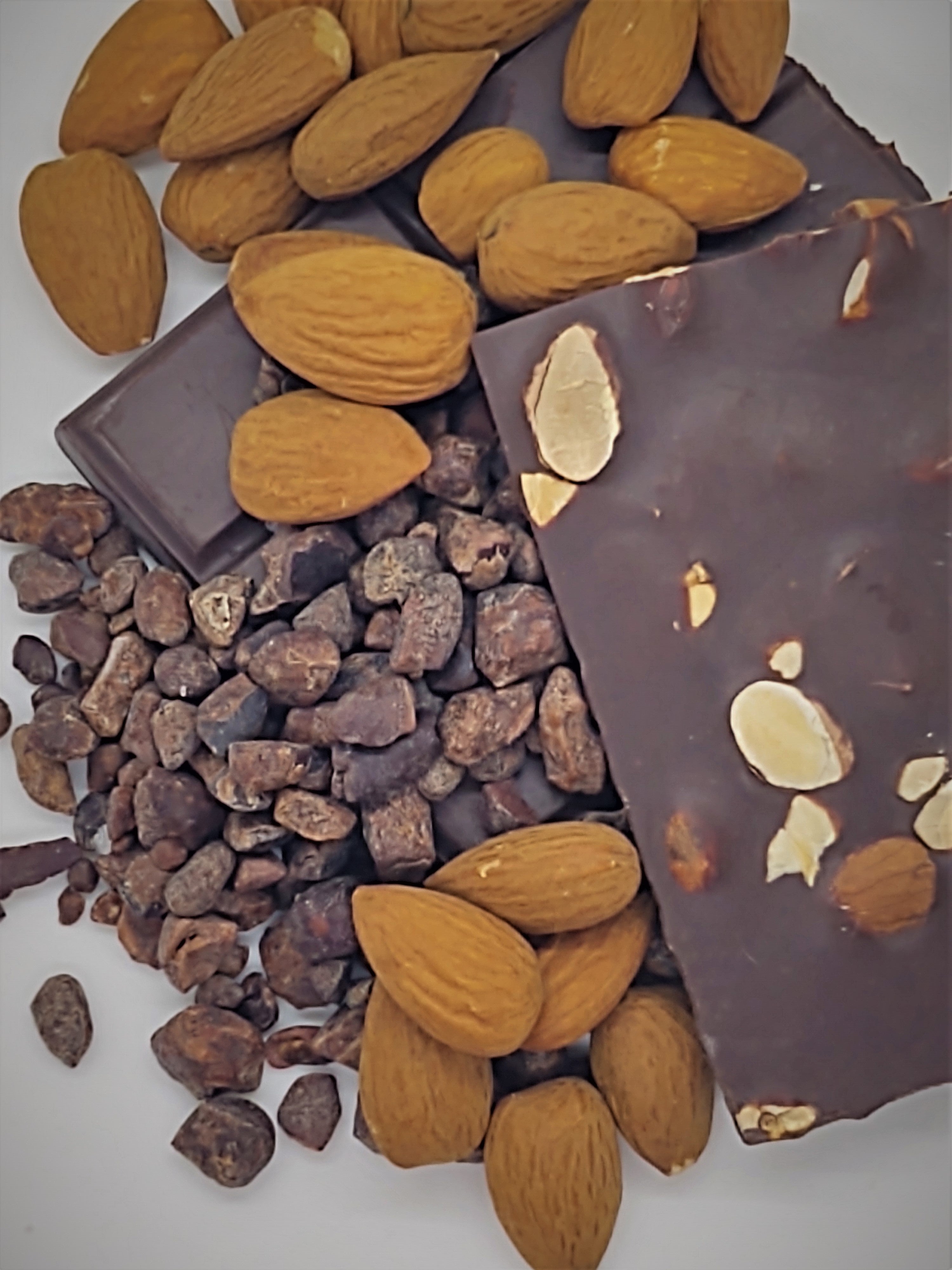 Pictured: solid dark chocolate bar with almonds. The bar is mounted by cocoa nibs and whole, roasted almonds